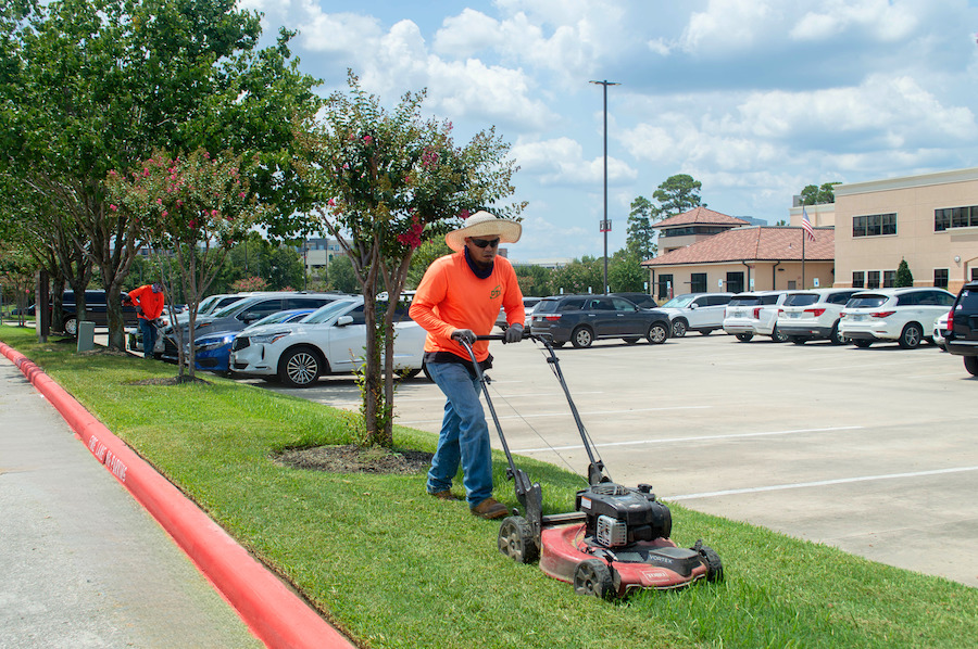 Landscapers Mowing Lawn in Houston Texas DTK Landscaping employee mowing lawn outside church property